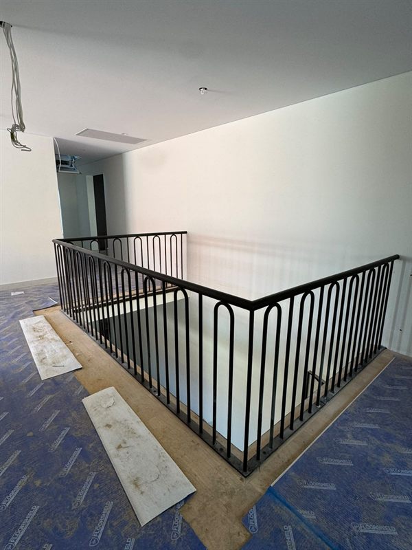 Black indoor stair balustrade with repeated arched metal bars