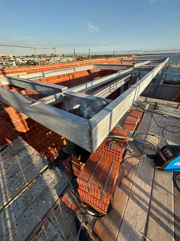 Welder working among steel beams on a brick construction site