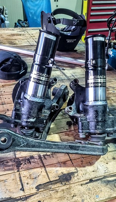 Two automotive strut assemblies with visible circumferential welds
